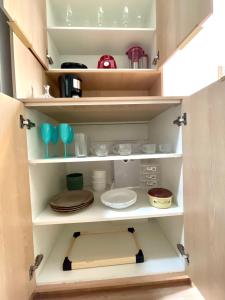 un armario lleno de platos en Apart Hotel Praia Ingá Quarto, Sala, 2 Varandas e Vista Parcial MAC, en Niterói