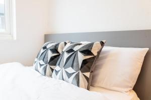 Una cama con almohadas blancas y negras. en Beautiful new build studio in London, en Sutton