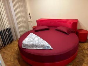 een rood bed met twee kussens erop bij Central Home Apartment in Craiova