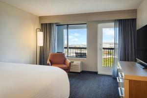 a hotel room with a bed and a chair and a window at Courtyard by Marriott Cocoa Beach Cape Canaveral in Cocoa Beach