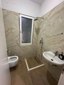 a bathroom with a sink and a toilet and a window at Eyar house in Kamëz