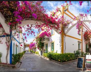 an alley filled with flowers in a town at Hola La Fuente in Puerto de Mogán