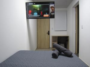 a bedroom with a bed with a tv on the wall at Lux Al Wafa in Bogotá