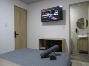 a bedroom with a bed with a television on the wall at Lux Al Wafa in Bogotá
