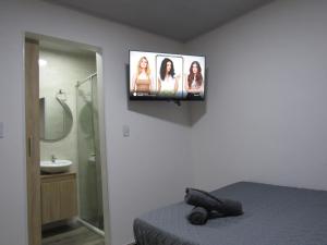 a bathroom with a tv on the wall with a bed at Lux Al Wafa in Bogotá