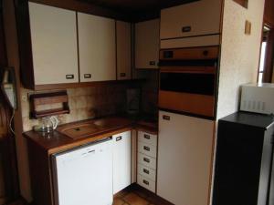 Studio en front de neige, 4 pers, balcon sud, proche des pistes - FR-1-815-29 في لو براز دي ليس: مطبخ صغير مع خزائن بيضاء وثلاجة