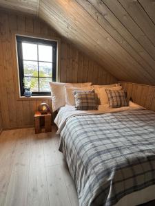 un letto in una stanza con una parete di legno di Fjellperlen, Hardangervidda a Eidfjord
