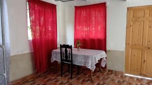 une salle à manger avec des rideaux rouges et une table avec deux chaises dans l'établissement Hospedaje Herradura de Rivas, à Rivas