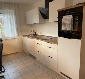eine Küche mit weißen Schränken und einem schwarzen Gerät in der Unterkunft Ferienwohnung Müller - Arberblick in Lohberg