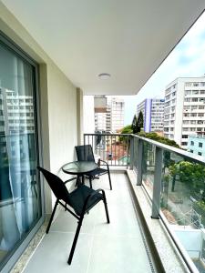 Un balcón con dos sillas y una mesa. en Apart Hotel Praia Ingá Quarto, Sala, 2 Varandas e Vista Parcial MAC, en Niterói