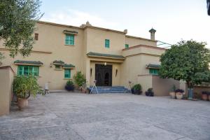 ein großes, hellbraunes Gebäude mit grünen Fenstern in der Unterkunft Bluegreen Guest House Marrakech in Aït Amara