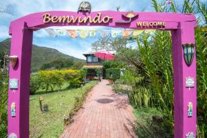 ein rosafarbener Torbogen mit einem Backsteinweg in der Unterkunft Pousada Villa Lagoa das Cores in Vale do Capao