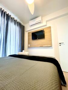 Un dormitorio con una cama con un televisor de pantalla plana en la pared. en Apart Hotel Praia Ingá Quarto, Sala, 2 Varandas e Vista Parcial MAC, en Niterói
