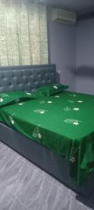 - un lit avec une couette verte et des fleurs dans l'établissement NEO HOME Gbawe, à Gbawe