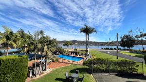 un complexe avec piscine et palmiers dans l'établissement Fishpen Views, à Merimbula