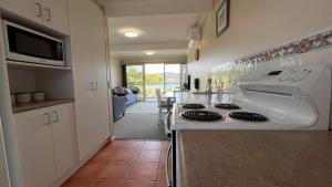 une cuisine avec une cuisinière blanche et un micro-ondes dans l'établissement Fishpen Views, à Merimbula