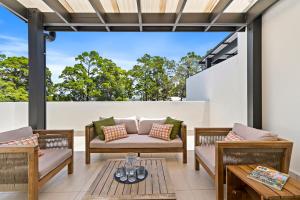 eine Außenterrasse mit 2 Stühlen und einem Tisch in der Unterkunft Noosa Dreaming in Noosa Heads