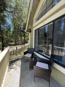 eine Veranda mit 2 Stühlen und Fenster zum Haus in der Unterkunft Woodsy Chic Family-Friendly Spacious Getaway in Lake Arrowhead