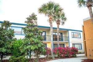 a building with palm trees and flowers in front of it at Royal Holiday Beach Resort in Biloxi