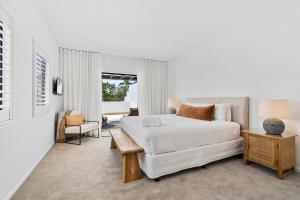 ein Schlafzimmer mit einem weißen Bett, einem Tisch und einem Stuhl in der Unterkunft Noosa Dreaming in Noosa Heads + 25 Fotos