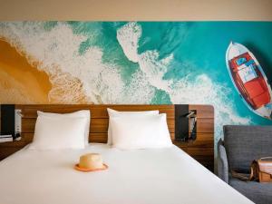 a bed with a hat sitting on top of it at Novotel Antibes Sophia Antipolis in Valbonne
