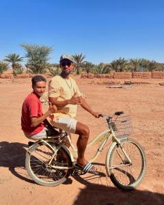 un homme et une femme assis sur un vélo dans le désert dans l'établissement Dar Nomad Tagounite, à Zagora