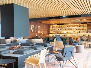 a lobby with tables and chairs and a restaurant at Novotel Rouen Sud Zenith Parc Expo in Saint-Étienne-du-Rouvray