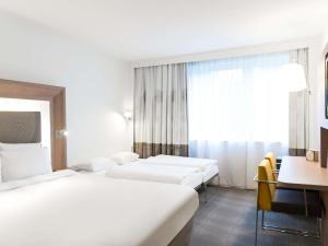 a hotel room with two beds and a desk at Novotel Brussels Airport in Diegem