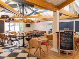 une salle à manger avec des tables, des chaises et un tableau noir dans l'établissement ibis Lyon Est Bron, à Bron