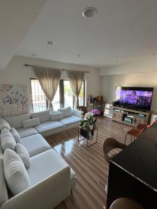 Il comprend un salon doté de canapés blancs et d'une télévision à écran plat. dans l'établissement Furnished 2bed 2bath by Hudson River, à West New York