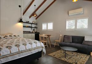 ein Schlafzimmer mit einem Bett, einer Couch und einem Tisch in der Unterkunft Duneluce in Tairua