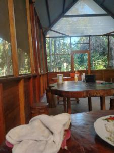 a room with a wooden table and a large window at Musas Garden Lodge Tambopata in Puerto Maldonado