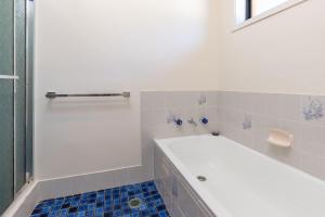 eine weiße Badewanne in einem Badezimmer mit blauen Fliesen in der Unterkunft Barrels at Boomerang in Boomerang Beach + 12 Fotos