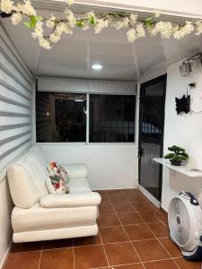 Apartamento en Santo Domingo Pablo mella morales في Hato Nuevo: غرفة معيشة مع أريكة بيضاء وبعض الزهور