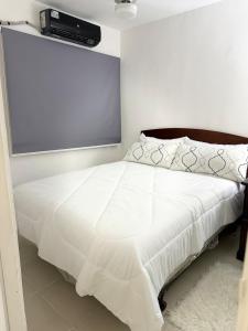 a bedroom with a white bed with a projector on the wall at Apartamentos en Pablo mellas morales 3ra etapa M-R42 Apt 101 Santo Domingo in Hato Nuevo