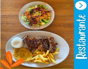 dois pratos de comida com batatas fritas e uma salada em Hotel Takuara em Vergara