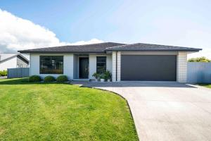 une maison avec un garage et une pelouse dans l'établissement 6 Bedrooms Hillside Lodge, à Rotorua