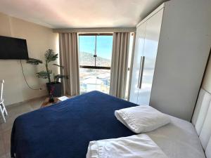 a bedroom with a blue bed and a large window at Eu Amo Arraial Hospedagem - Sophia I Orla Praia Grande in Arraial do Cabo +34 photos
