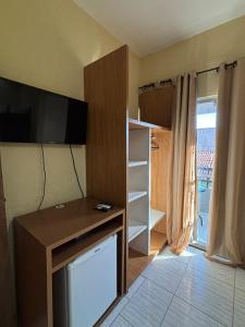 Habitación con escritorio, TV y armario. en Pousada Praia Dos Encantos, en Japaratinga