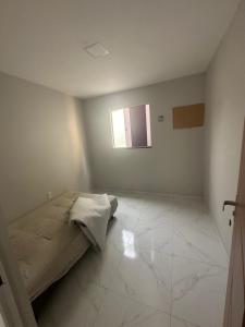 ein weißes Zimmer mit einem Bett und einem Fenster in der Unterkunft Casa temporada in Cabo Frio