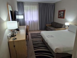 a hotel room with a bed and a couch at Novotel Manchester West in Worsley