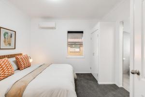 ein weißes Schlafzimmer mit einem Bett und einem Fenster in der Unterkunft Stylish Inner-City Stay! in Toowoomba
