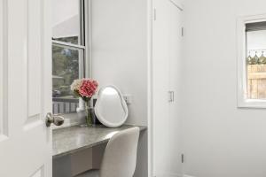 ein Badezimmer mit einem Spiegel und einer Vase aus Blumen auf der Theke in der Unterkunft Stylish Inner-City Stay! in Toowoomba + 18 Fotos