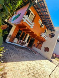 an orange building with chairs on a brick road at Hotel Trevo do Porto in Porto Seguro