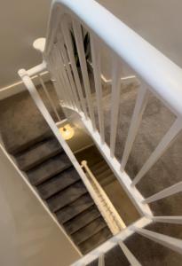 a spiral staircase with a white stair case at Stylish 2BD, Near O2, WIF, Sleeps 6, London in London