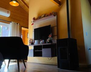 een woonkamer met een flatscreen-tv en een stoel bij Chalé Bienz - Hospedagem Rural in Urubici