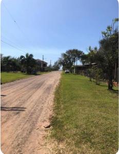 an empty dirt road with grass and houses on it at Casa de praia - 2 quadras do mar in Arroio do Sal