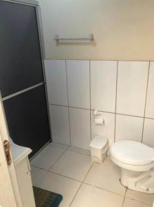 a white bathroom with a toilet and a shower at Casa de praia - 2 quadras do mar in Arroio do Sal +1 photo