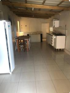 a large kitchen with a table and a refrigerator at Casa de praia - 2 quadras do mar in Arroio do Sal