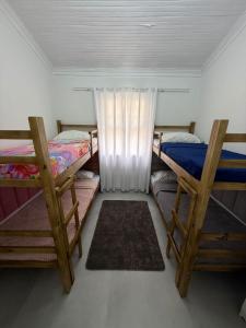 una stanza con tre letti a castello e due tappeti di Casa Bertioga Centro a Bertioga